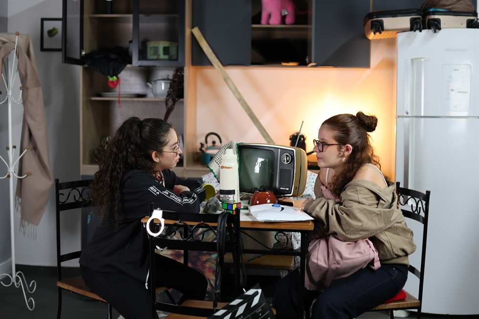 Duas atrizes contracenando em set de cozinha montado